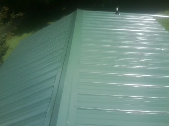 New green metal panels meeting at the ridge of a roof — Flat Roof Repair work by our crew in Selma